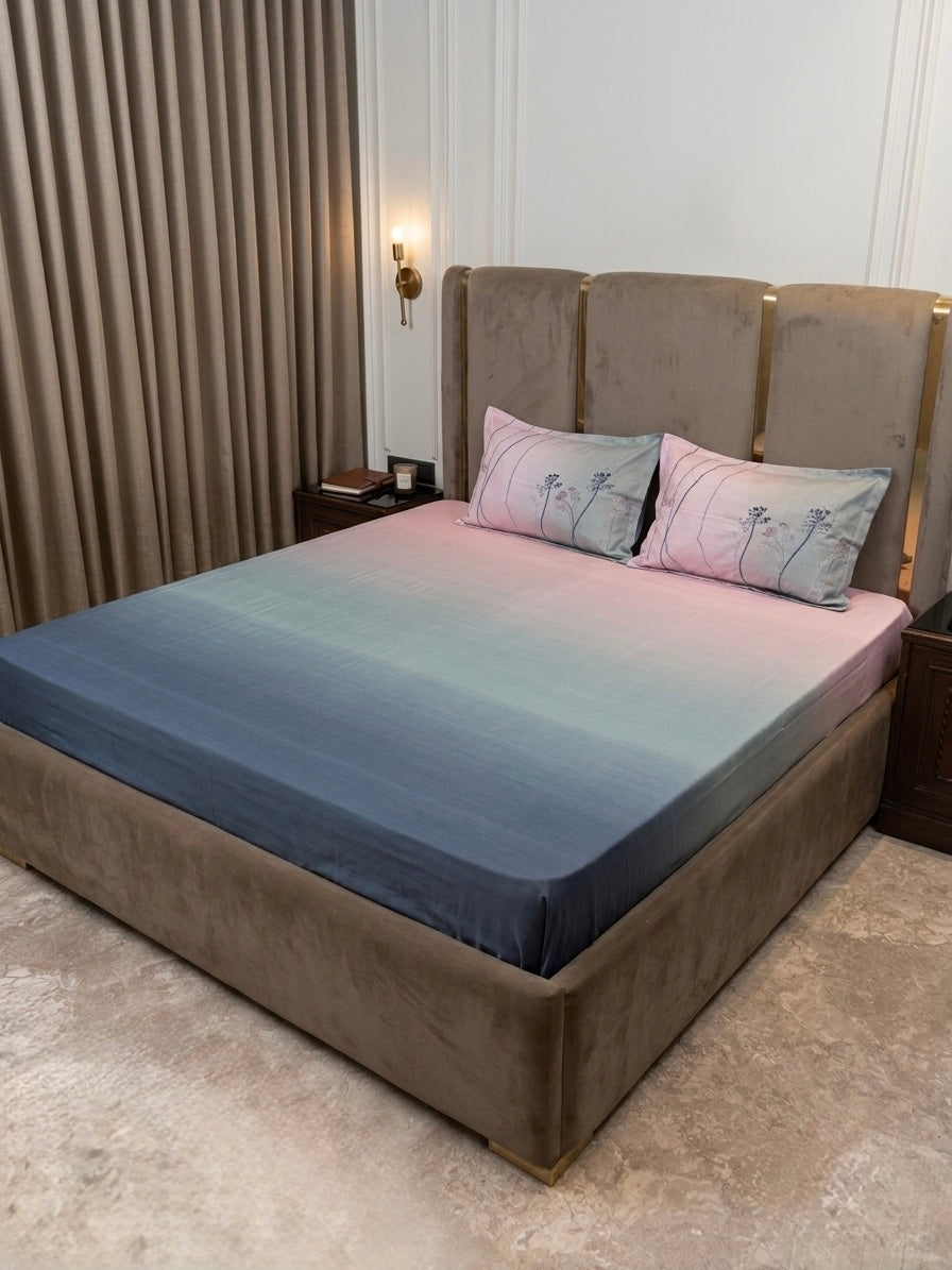 A modern bedroom with a large upholstered bed features a Percale Ombre 250 TC King Size Bedsheet and Pillow Cover Set (Navy Blue Ombre), paired with dark bedside tables and beige curtains for a sophisticated look.
