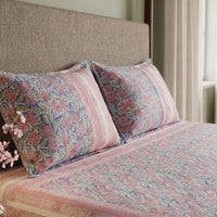 Bed with floral-patterned bedding and pillows in a bedroom setting.