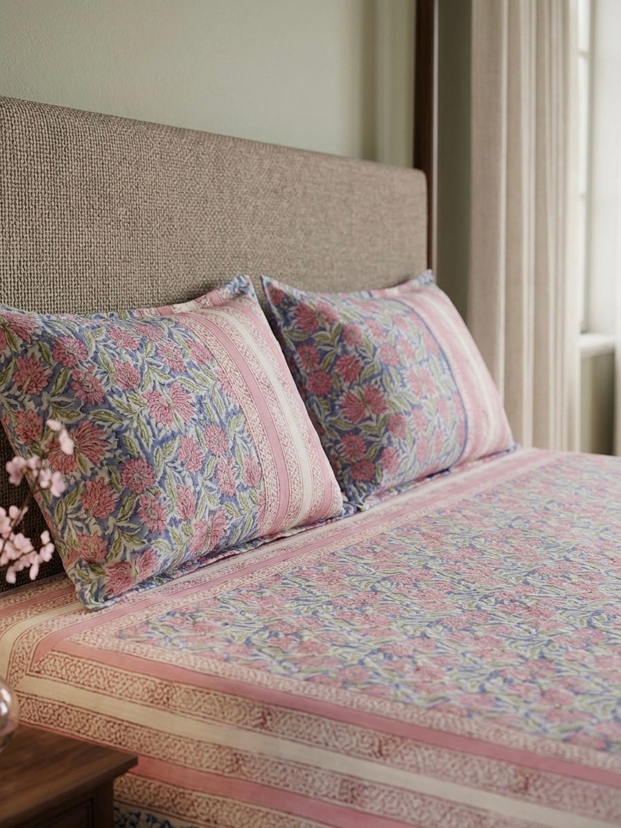 Bed with floral-patterned bedding and pillows in a bedroom setting.