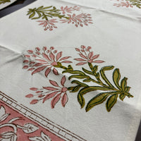 Close-up of a fabric with floral patterns in pink and green on a white background.