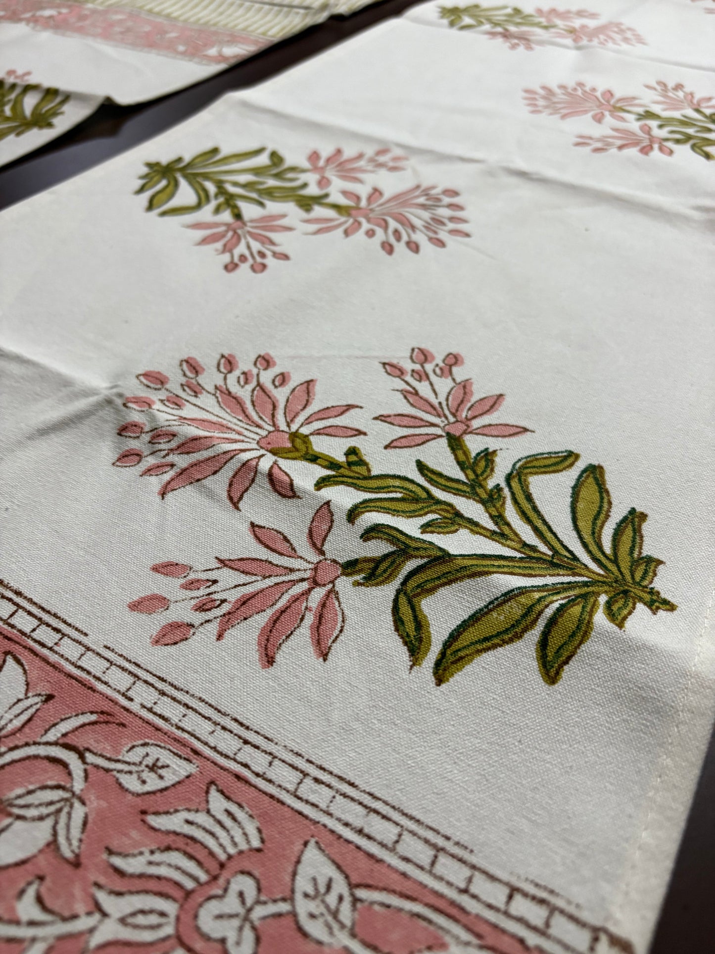 Close-up of a fabric with floral patterns in pink and green on a white background.