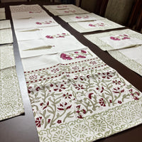 Table setting with floral-patterned placemats and a runner on a wooden table.