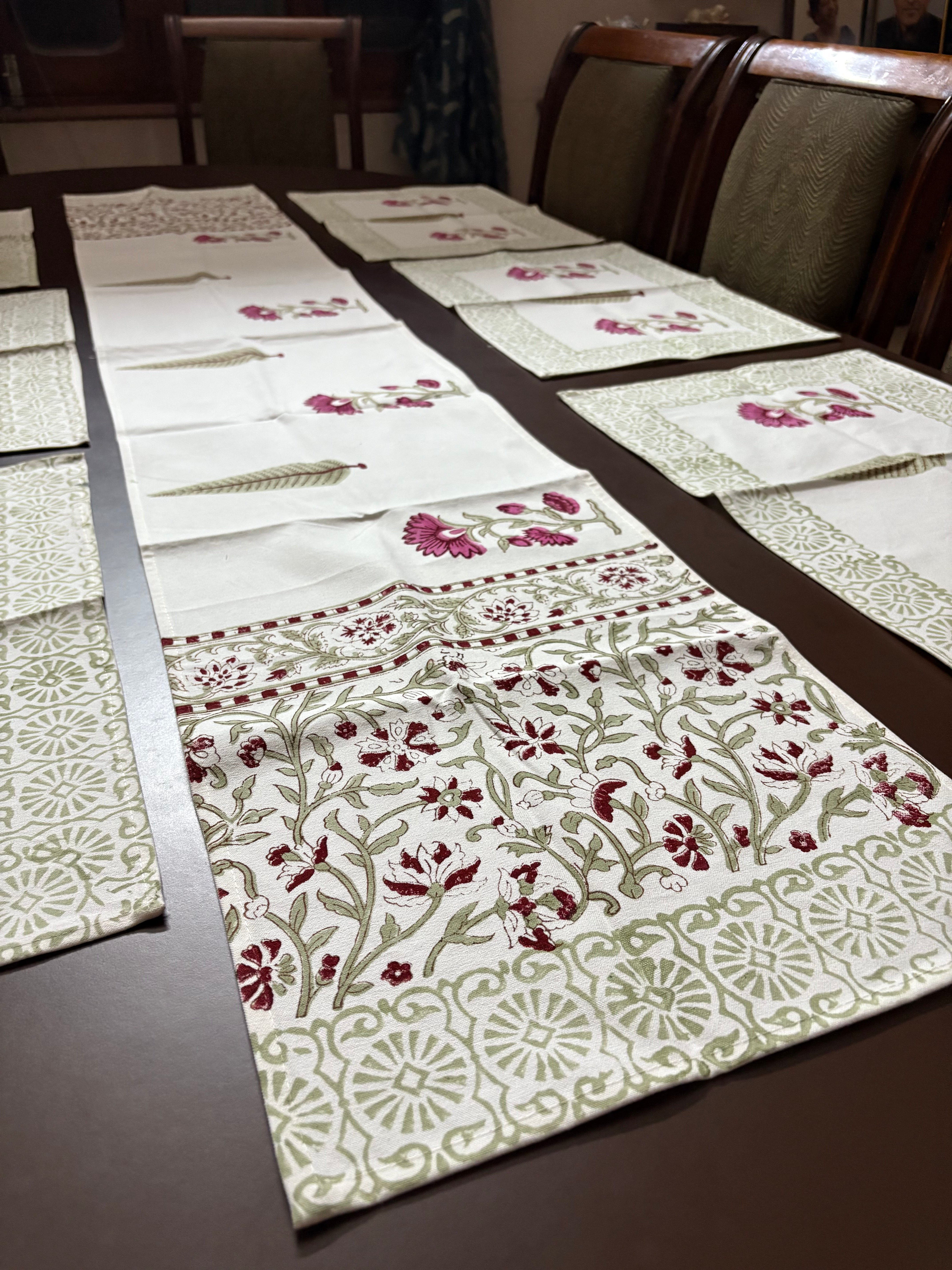 Table setting with floral-patterned placemats and a runner on a wooden table.