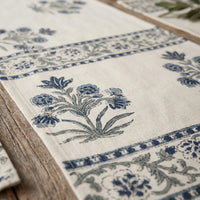 Close-up of a decorative table runner with floral patterns on a wooden surface.
