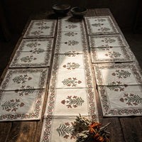 Set of patterned table runners and placemats on a wooden table with a dark background