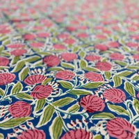 Close-up of floral fabric with pink flowers and green leaves on a blue background