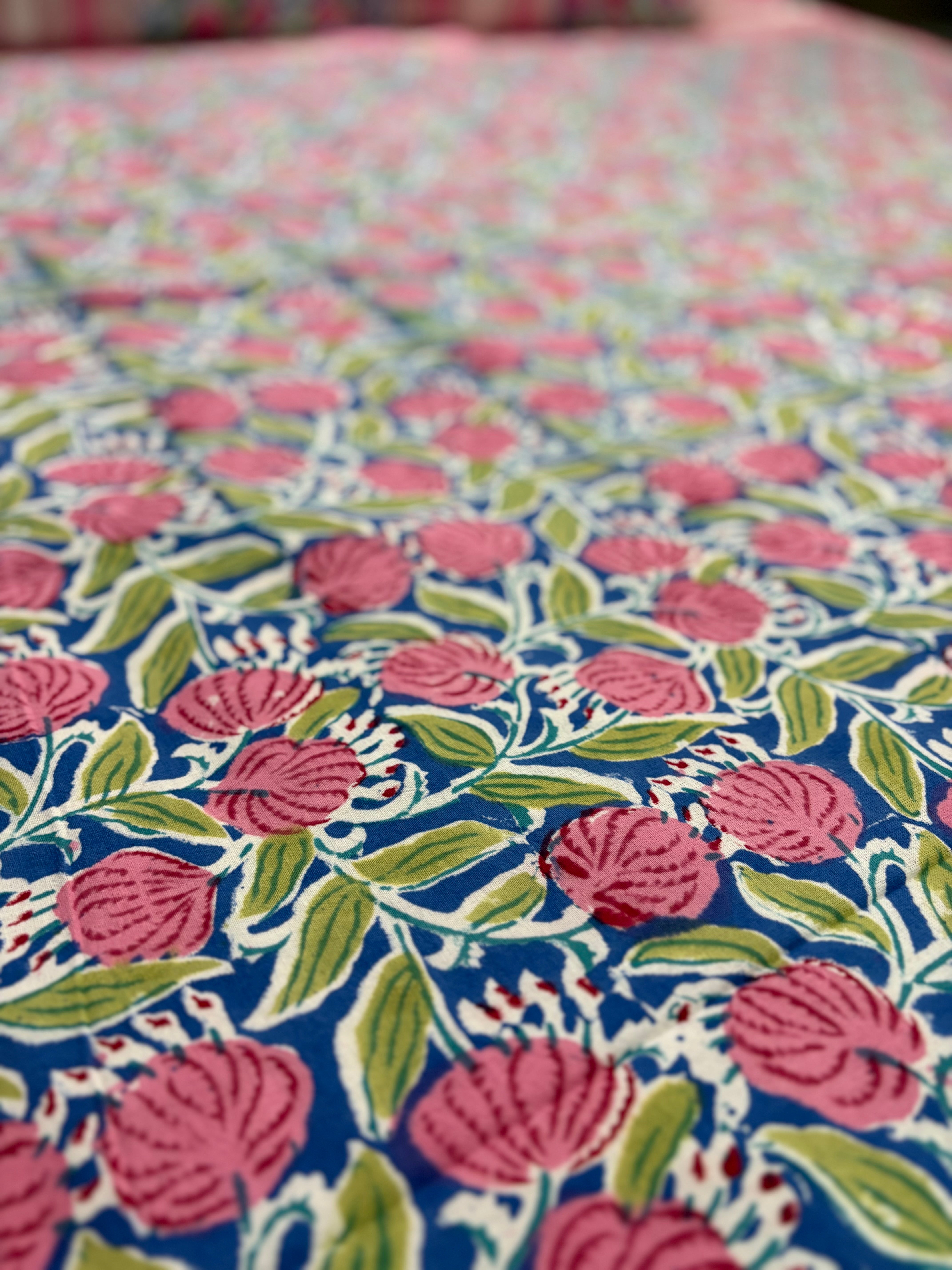 Close-up of floral fabric with pink flowers and green leaves on a blue background