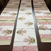 Decorative table runner with floral and striped patterns on a wooden table.100% authentic handblock printed fabrics by savai home. Indian textiles
