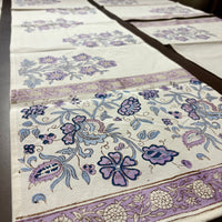 Floral patterned fabric with purple and blue designs on a white background block printed table linens