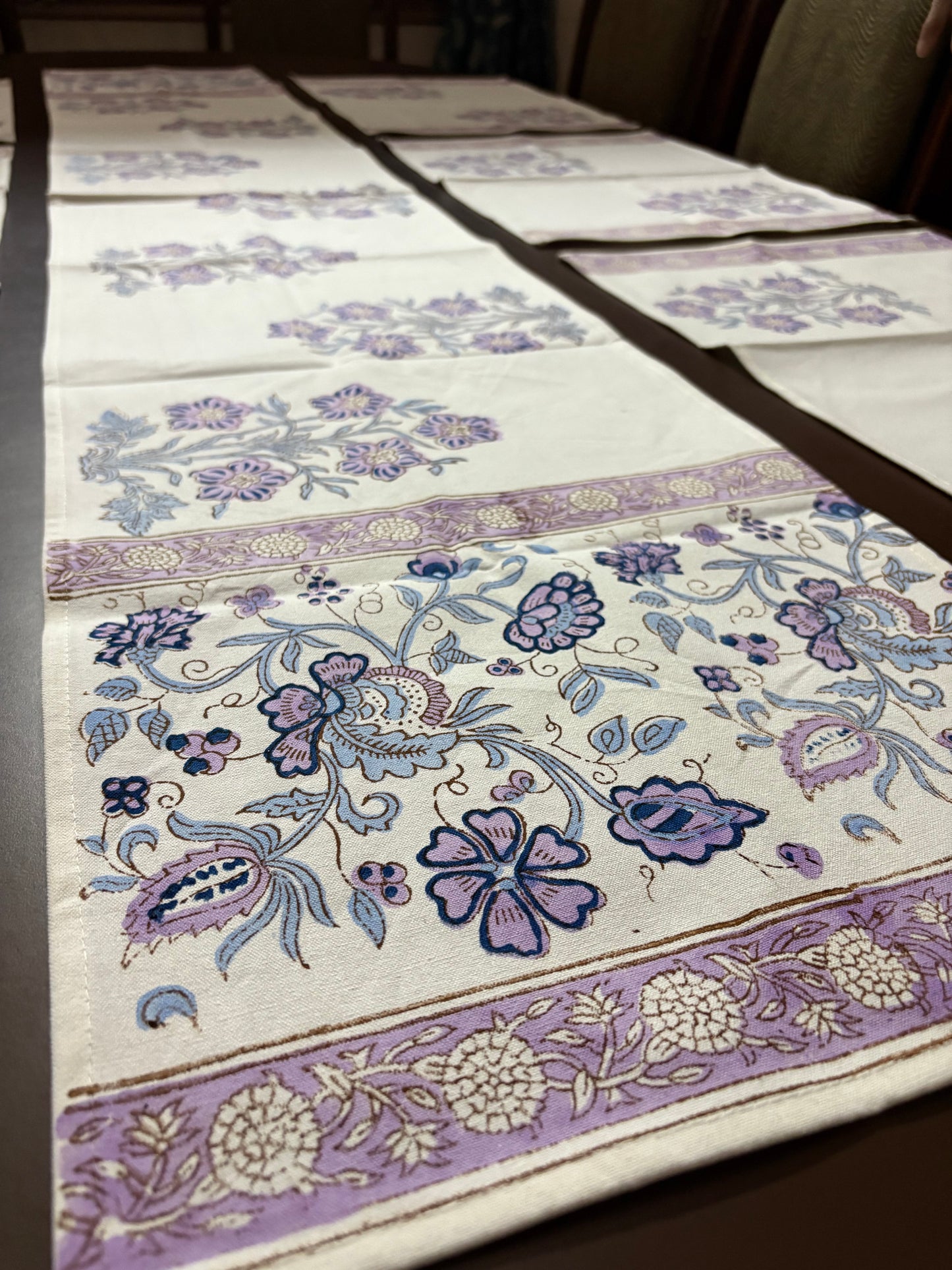 Floral patterned fabric with purple and blue designs on a white background block printed table linens