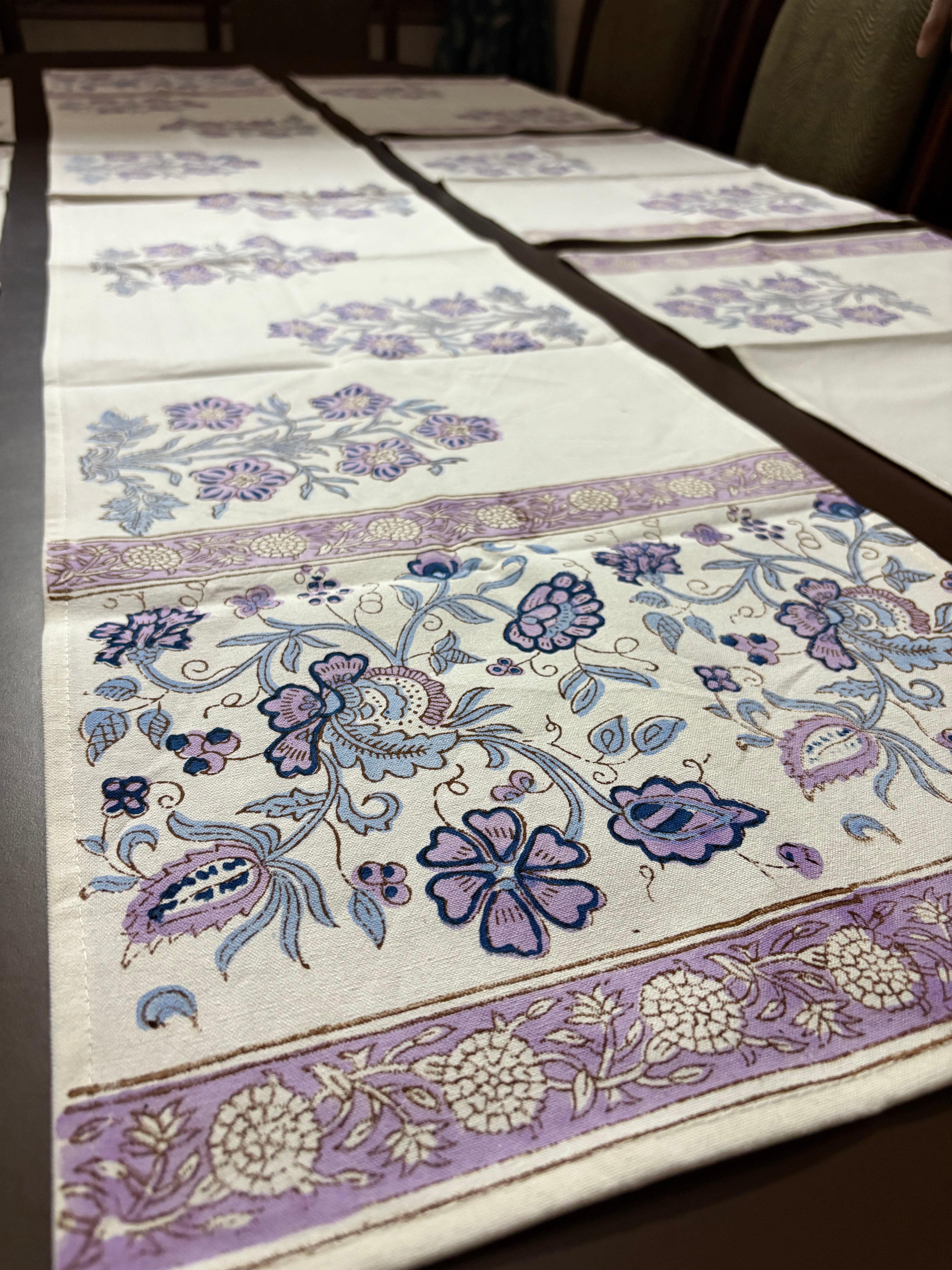 Floral patterned fabric with purple and blue designs on a white background block printed table linens