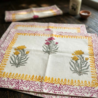 Block printed floral placemats with floral designs on a wooden surface. 100% handblock printed art pieces made in india. Indian textiles