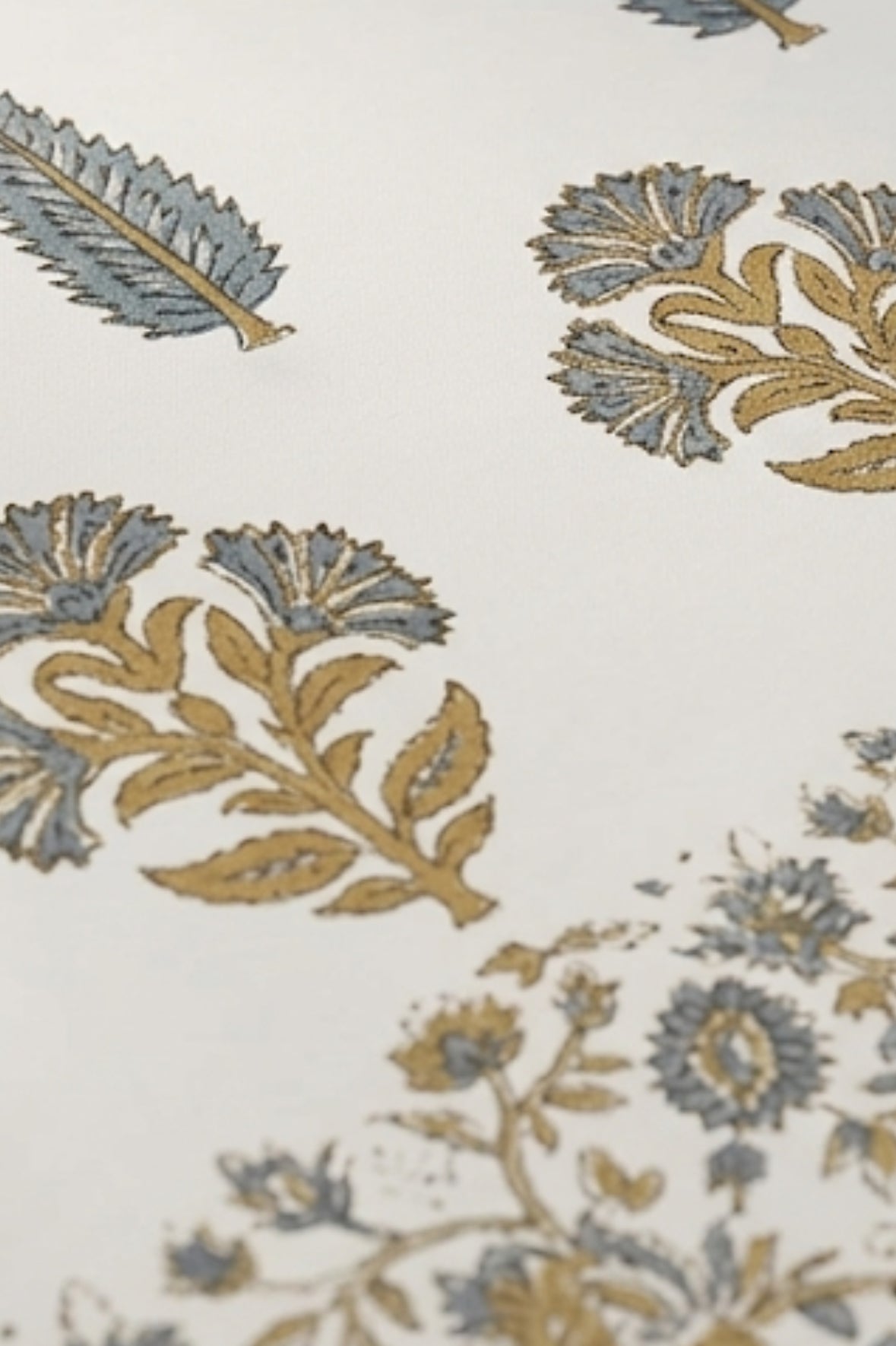 Close-up of a floral block printed patterned fabric with blue and gold colors on a white background.