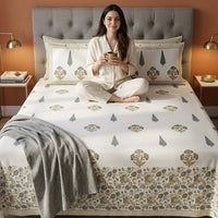 Woman sitting on a bed with Hand block printed bedding in a bedroom setting.
