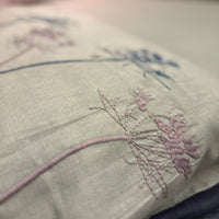 A close-up of the Percale Ombre 250 TC Bedsheet + Pillow Cover Pair Set (King Size), featuring delicate ombre floral patterns in purple and blue on 100% cotton, with a blurred bed and pillow in the background for a luxury hotel vibe.