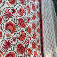 Close-up of a fabric with red floral pattern on a white background Sanganeri print Dohars Block printed