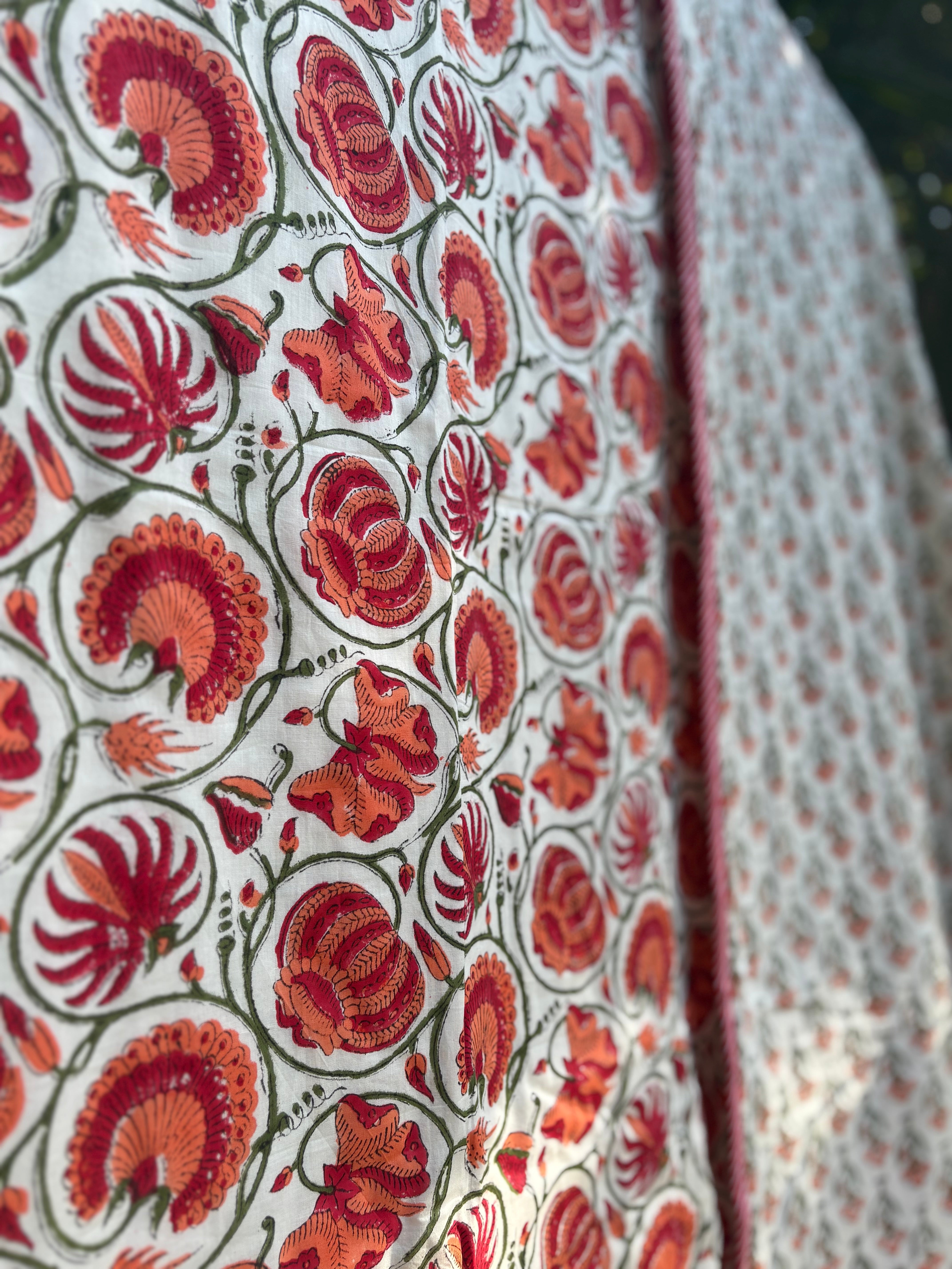 Close-up of a fabric with red floral pattern on a white background Sanganeri print Dohars Block printed