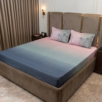 A modern bedroom with a large upholstered bed features a Percale Ombre 250 TC King Size Bedsheet and Pillow Cover Set (Navy Blue Ombre), paired with dark bedside tables and beige curtains for a sophisticated look.