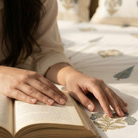 Person reading a book on a bed with block printed floral bedding